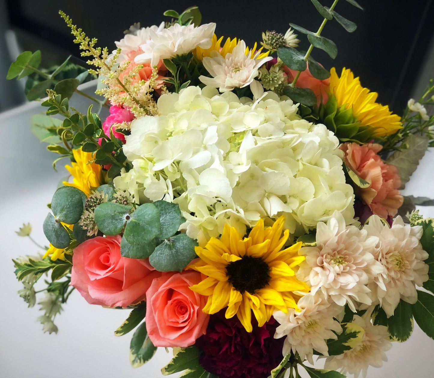 sunflowers hydrangeas and roses in a glass vase